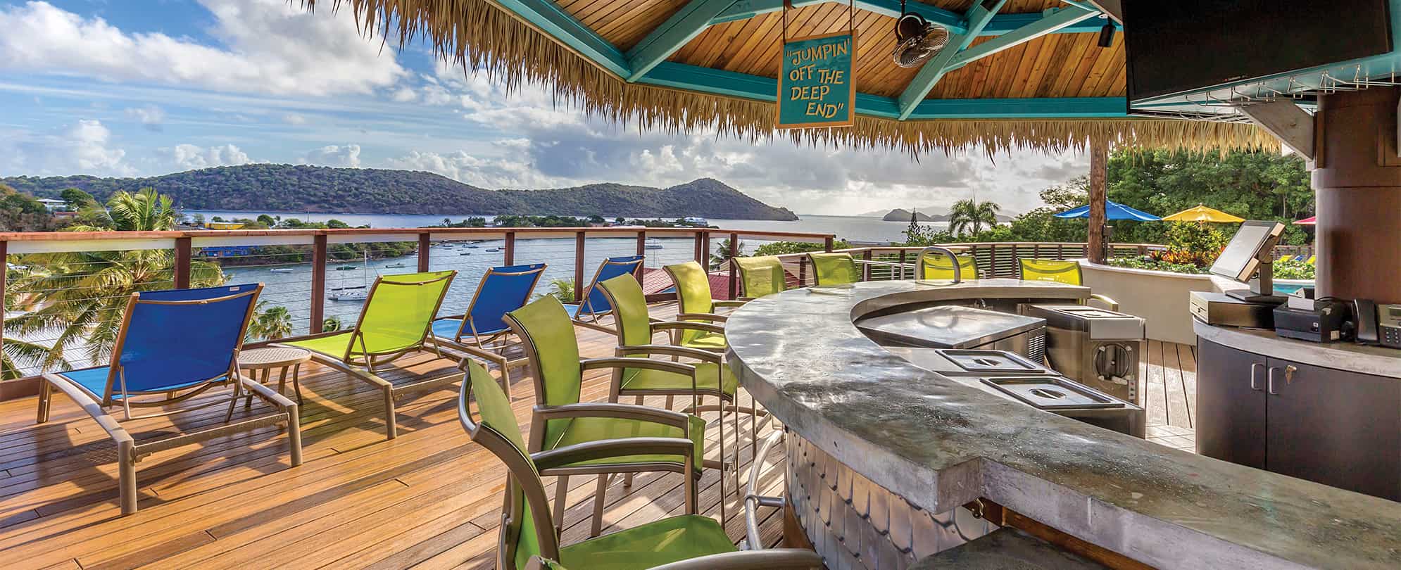 Bright blue and green chairs around a tiki bar overlooking the ocean at Margaritaville Vacation Club by Wyndham - St. Thomas