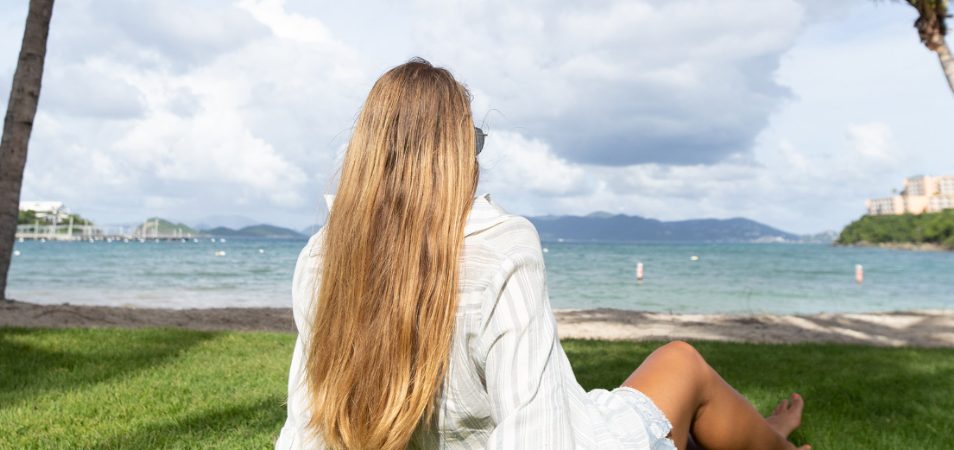 Woman with long blonde hair sits looking out over the ocean at a Margaritaville Vacation Club resort.