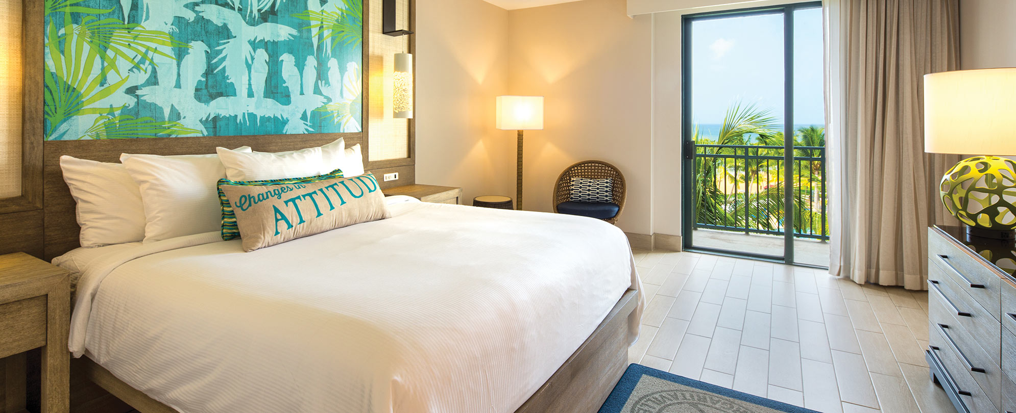 A king-size resort bed with crisp white linens in a Margaritaville Vacation Club suite with an ocean view.