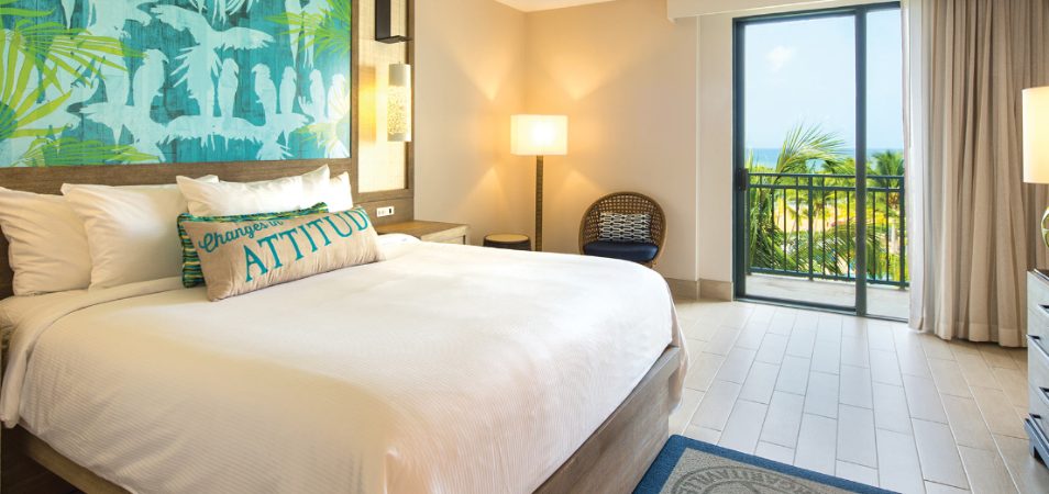 A king-size resort bed with crisp white linens in a Margaritaville Vacation Club suite with an ocean view.